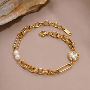 Macro view of gold stainless steel bracelet featuring a heart zircon and two pearls.