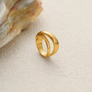 Gros plan d'une bague minimaliste en acier inoxydable doré au design fluide double