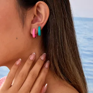 Close-up detail of dopamine colored enamel C-shaped hoop earrings worn on an ear.