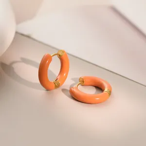 Close-up detail of vibrant orange enamel and gold finish on stainless steel hoop earrings.