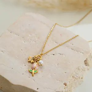 Detailaufnahme einer goldenen Halskette mit Tulpen- und Bienenanhänger auf Stein