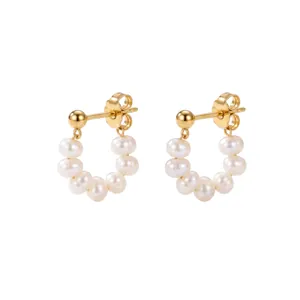 Detalle de pendientes de aro de acero dorado con perlas de agua dulce naturales.