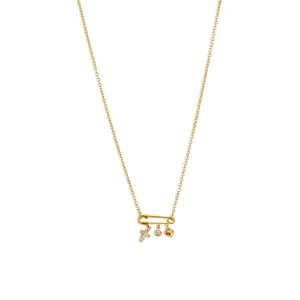 Detalle de collar con colgante de imperdible dorado con dijes de corazón y cruz