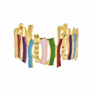 Primo piano delle strisce verticali in smalto colorato sul bracciale dorato aperto.