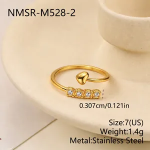 Vista macro di un anello aperto in acciaio dorato con cuore e intarsio di cristalli e specifiche