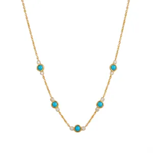 Primer plano del collar de acero dorado con piedras turquesas y circonitas brillantes