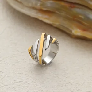 Détail montrant le motif de feuille géométrique et la finition or-argent de la bague