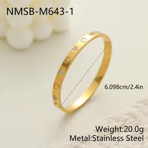 Primer plano de un brazalete de acero inoxidable dorado con corazones y medidas