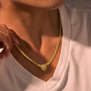Gedetailleerde macro-opname van een vergulde hartjesketting bij een model in het wit