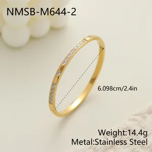 Primer plano de un brazalete de acero inoxidable dorado con cristales y medidas.