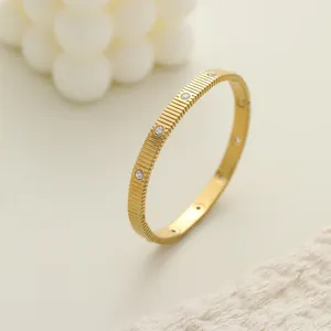 Vista detallada de un brazalete de acero dorado con textura estriada y piedras
