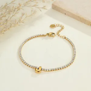 Detail eines goldenen Edelstahl-Tennisarmband mit einem minimalistischen J-Anhänger