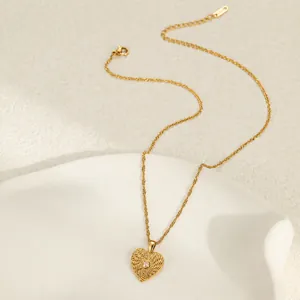 Close-up of textured gold heart pendant necklace with center rhinestone detail