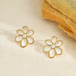Gros plan sur d'élégantes boucles d'oreilles fleur en émail blanc et perle