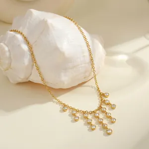 Elegant gold stainless steel tassel necklace with round cubic zirconia on white seashell