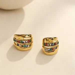 Primer plano de pendientes de acero chapado en oro con piedras de circón de colores