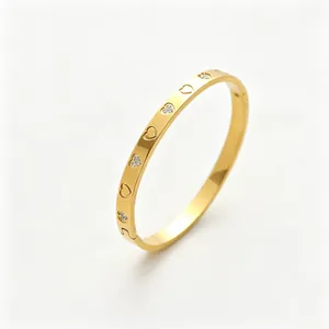 Detalle de brazalete chapado en oro con grabado de corazones y cristales brillantes