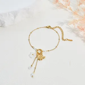 Detailansicht eines vergoldeten Armbands mit Bienen- und Blumenanhänger auf weißem Grund.