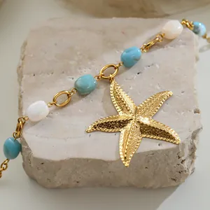 Detail view of ocean-style gold starfish pendant with blue and white beads.