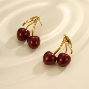 Close-up of vintage style red enamel cherry earrings featuring elegant golden stems