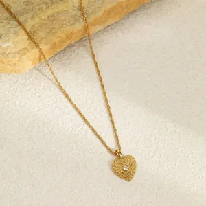 Detailed close-up of a gold-plated stainless steel heart pendant with spiral texture