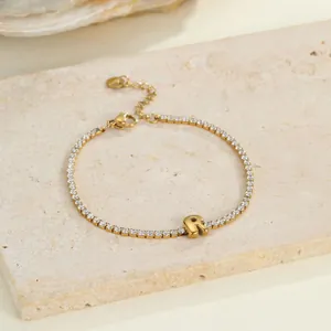 Detailaufnahme eines goldenen Edelstahl-Tennisarmbands mit Buchstabe R Anhänger