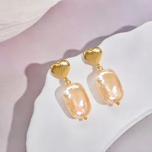 Vue détaillée des boucles d'oreilles cœur en perles baroques dorées au lustre irisé
