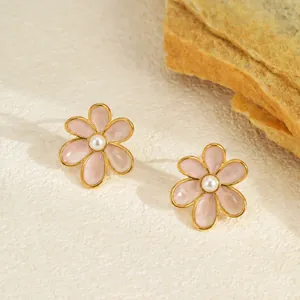 Vue macro élégante de boucles d'oreilles fleur en émail rose avec perles sur pierre