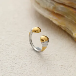 Primer plano de anillo abierto de acero bicolor con diseño de frijol y textura rugosa