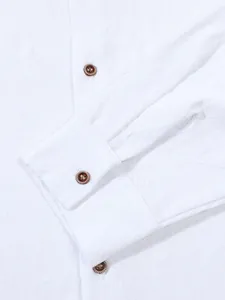 Detailed macro view of white linen shirt cuff showing textured fabric and brown buttons