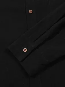 Detailed macro shot of a black linen shirt cuff with decorative button accents