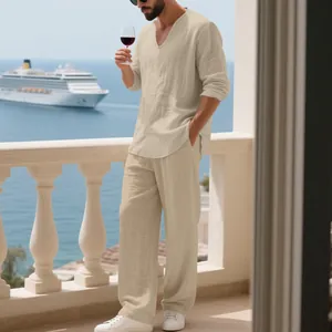 Mann in beigem Leinen-Resort-Set auf Balkon mit Meerblick und Kreuzfahrtschiff.