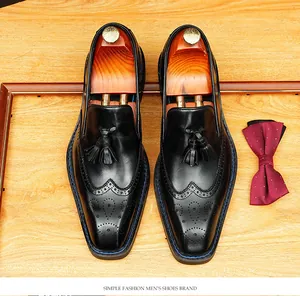 Detailed top view of handmade black leather tassel loafers with elegant brogue carvings
