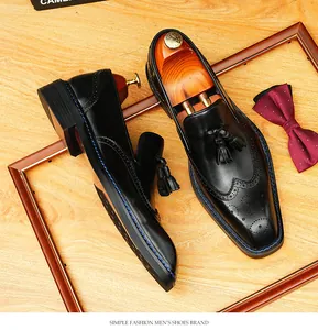 Close-up detail of black leather brogue loafers with tassels and square toe design.