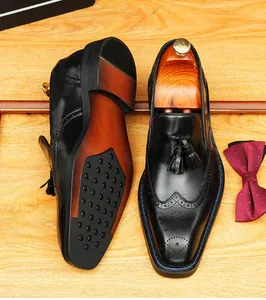 Detailed macro view of men's black leather tassel loafers with brogue wingtip design