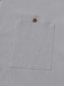 Macro view of men's casual grey linen shirt chest pocket and brown button texture