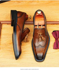 Detail view of brown leather brogue tassel loafers with wingtip perforations