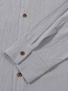 Close-up of grey linen shirt fabric texture and decorative wooden button cuff detail