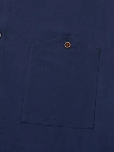 Close-up macro detail of a navy blue linen casual shirt showing the chest pocket and button