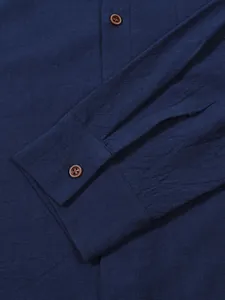 Detailed macro view of navy blue linen-blend fabric texture and button on men's shirt