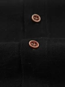 Detailed macro view of decorative brown buttons on a black linen casual shirt for men