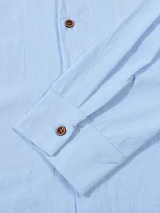 Macro view of light blue linen-textured shirt sleeve cuff with classic brown wooden buttons