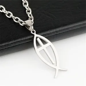 Close-up detail of a polished stainless steel fish pendant with a cross design.