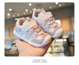 Vue rapprochée de baskets de marche roses pour bébés avec velcro et semelle souple dans la main