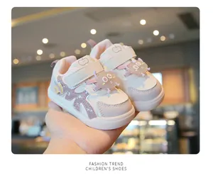 Close-up of pink baby girl sneakers with cute cartoon charms and soft sole