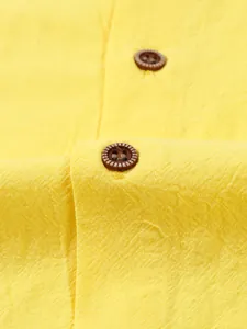 Close-up detail of yellow linen fabric texture and wood-style buttons on a men's casual shirt.