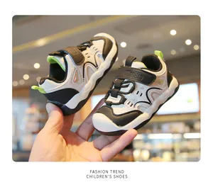Vue détaillée des baskets pour enfants noir et blanc à semelle souple, tenues à la main