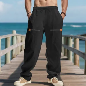 Vue détaillée d'un pantalon noir en lin avec poches zippées sur un ponton de plage.