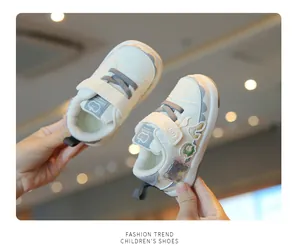 Detailed view of white toddler walking shoes with colorful bear patches and velcro strap