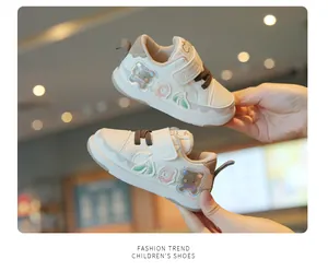Detailed view of cream-colored baby walking shoes with bear and donut patches